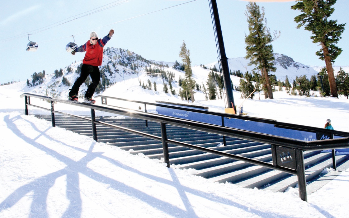 Snowboarder riding a rail on a sunny day